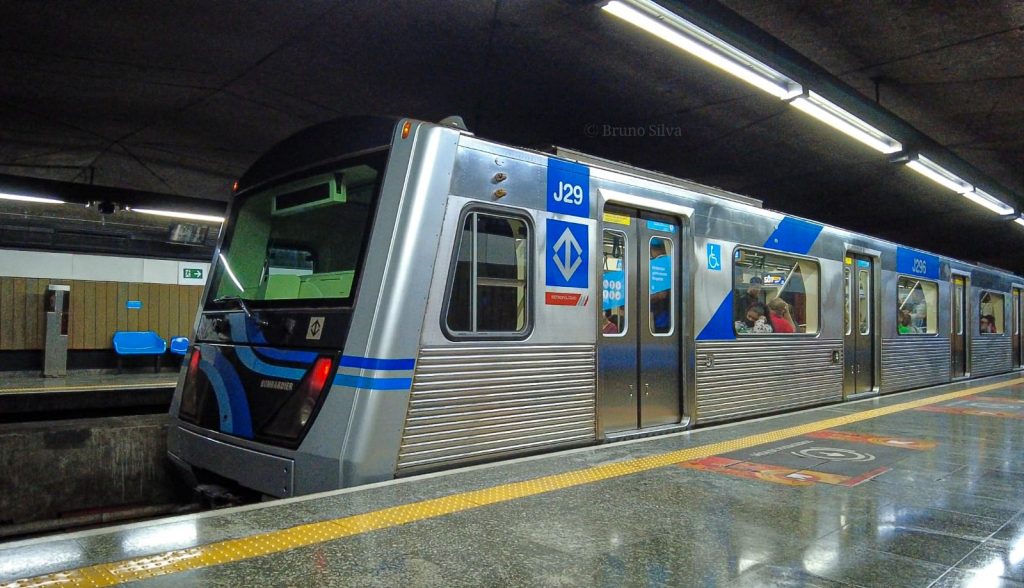 Metrô da linha 1 azul de São Paulo na plataforma de embarque, visto lateralmente.